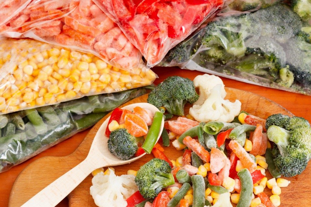 Frozen vegetables on cutting board and plastic bags