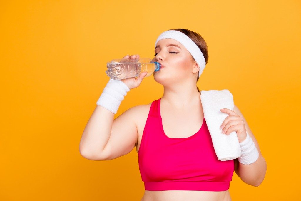 woman in workout clothes drinking water