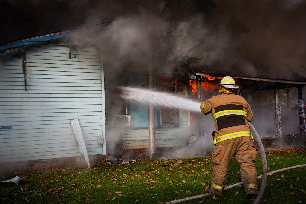 a firefighter putting out the fire of a house