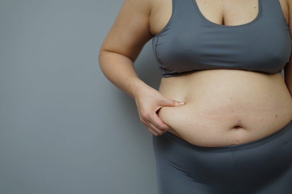 overweight woman pinching her stomach