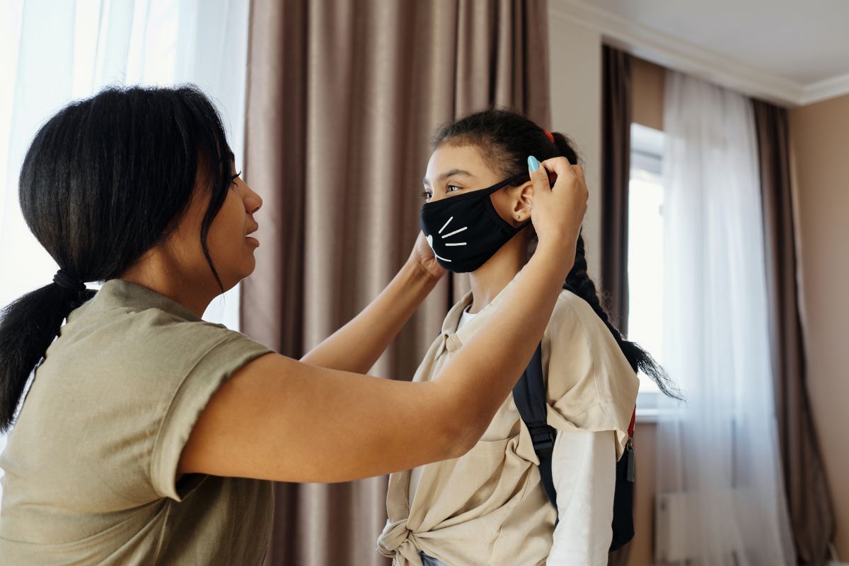 woman putting face mask with cat whiskers on child