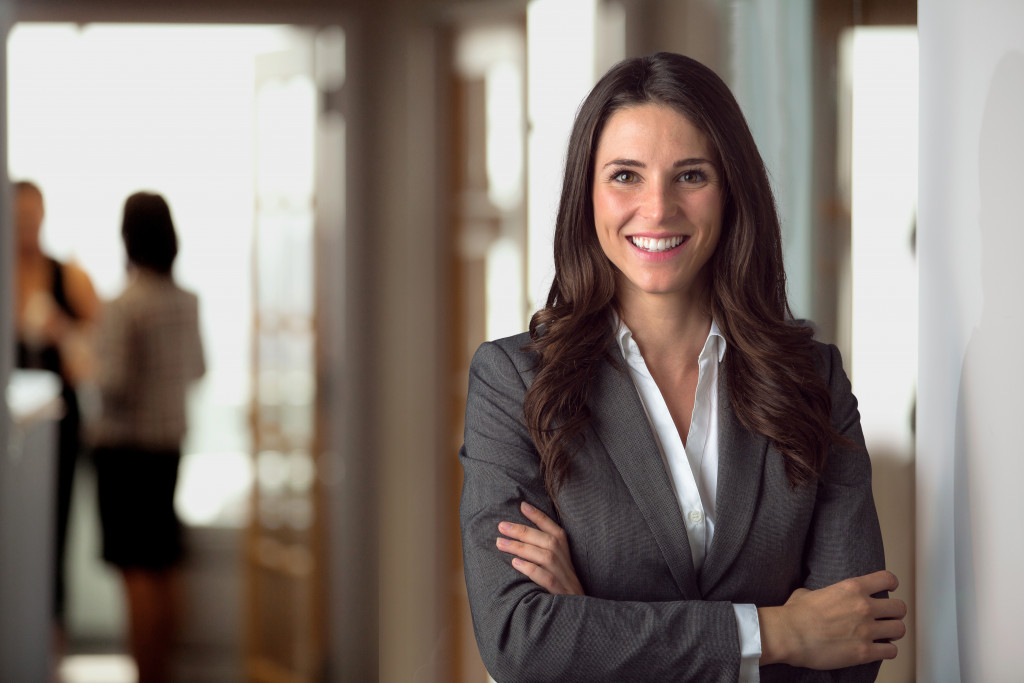 woman wearing corporate attire smiling while crossing her arms confidently
