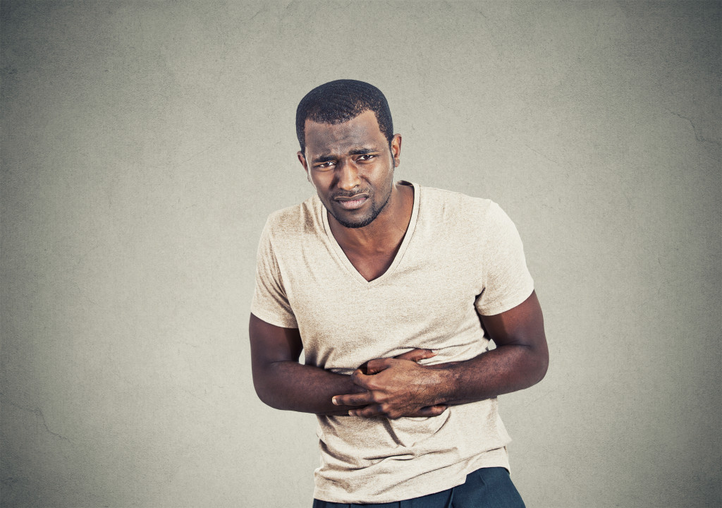 man clutching his belly because of stomach pain