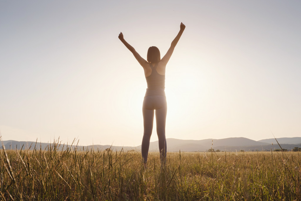 A woman raising her arms after a successful morning jog