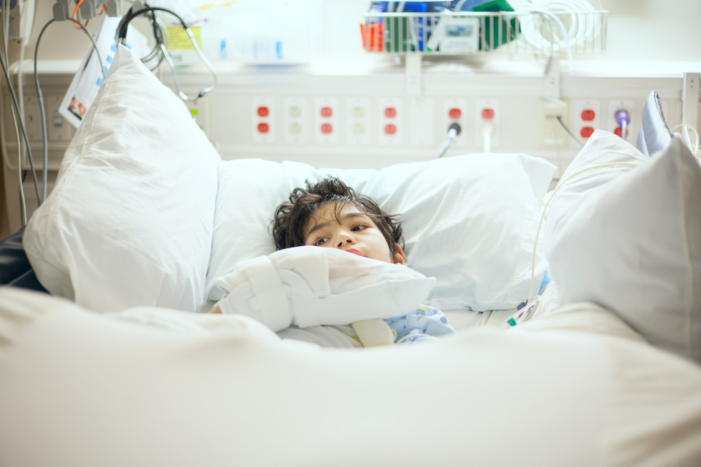 A child with a rare disease lying alone on a hospital bed with a hose hooked up to them