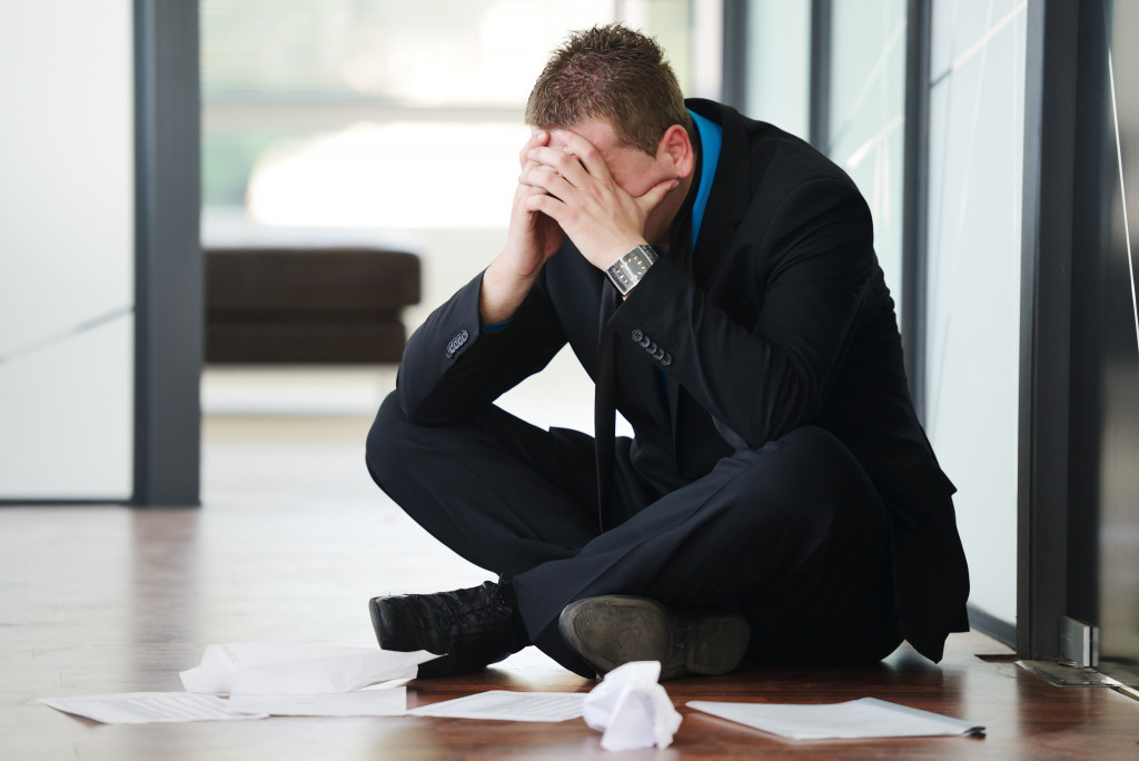 A stressed person on the floor with papers around him