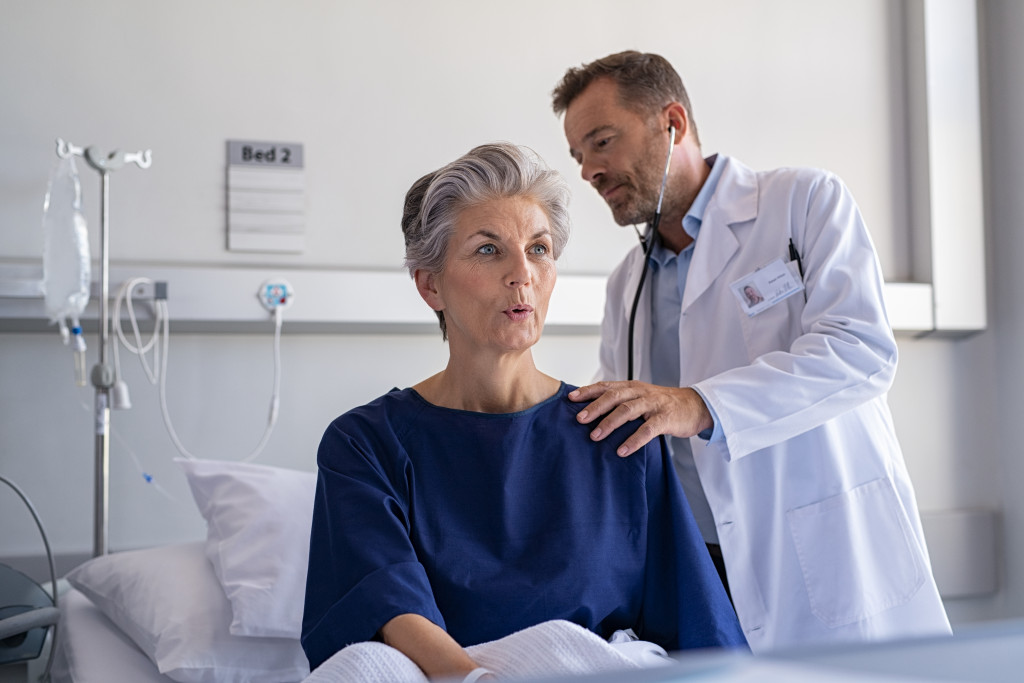 physician listening to senior woman's lungs
